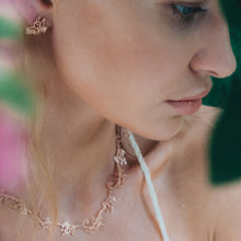 Model is wearing rose-gold toned blush silver Baby B butterfly stud earrings 